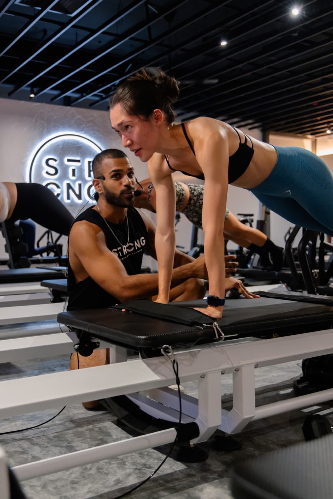 Aluna em pose de Pilates em equipamento Reformer